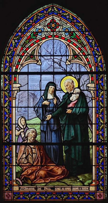 <b>St Vincent de Paul</b>, accompagné de <b>Louise de Marillac</b>, tient un enfant et tend la main à un mendiant. A l’arrière-plan, on aperçoit l’hospice de Bicêtre.